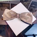Detailed view of champagne gold rhinestones on a luxury bow hair clip with fabric base - Champagne