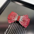 Gros plan de la barrette nœud rouge ornée de strass bicolores brillants et festifs - Pince à Ressort Couleur Dégradée Avec Strass / Rouge