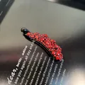 Détail d'une pince à cheveux de luxe rouge avec strass sur un magazine vintage - Pince Banane à Bord Ondulé Avec Strass / 8cm / Rouge