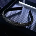 Close-up of black micro-paved rhinestones on a slim headband with sparkling luxury texture - Gray