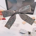 Gros plan d'une barrette à cheveux en forme de nœud ornée de strass gris foncé brillants - Style Strass Gris Minéral