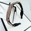 Dettaglio di un cerchietto nero con nodo e strass champagne scintillanti su sfondo bianco - Strass Champagne