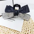 Détail de pince à cheveux vintage à nœud en satin noir avec des strass scintillants - Zircon Blanc
