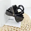 Détail d'une pince à cheveux noire à nœud avec des strass étincelants sur fond cadeau - Moyen (8cm) / Strass Gris Minéral