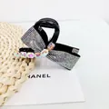 Gros plan sur la pince à cheveux nœud noir élégante avec strass et cristaux arc-en-ciel - Zircon AB