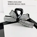 Macro view of crystal rhinestones on a black bow hair claw clip for elegant hair styling - White Zircon