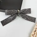 Macro detail of a crystal-encrusted bow hair clip with shimmering rhinestones - Black