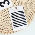 Detail von zwölf matt schwarzen minimalistischen Haarklammern auf einer weißen Displaykarte - Schwarz Gebogener Feiner Stil
