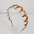 Dettaglio di un cerchietto ondulato marrone tartarugato con design flessibile a zigzag - Stile Caffè con Denti Grandi / caffè