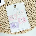 Set mit vier sternförmigen Haarklammern in Macaron-Farben auf weißer Karte - Rosa Bär