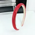 Détail du serre-tête rembourré rouge avec strass denses sur support minimaliste - Rouge