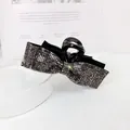 Detalle macro de la pinza de pelo con lazo de diamantes de imitación oscuros sobre negro - Estilo Strass Gris Mineral