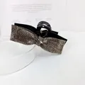 Close-up of elegant black hair claw clip with shimmering rhinestones in a bow shape - Transparent Gray Rhinestone Style