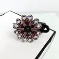 Macro view of large flower hair claw clip with pink rhinestones on black acrylic base - Purple