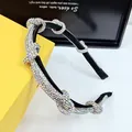 Detailed close-up of crystal knots on black headband against a yellow jewelry box - AB Zircon