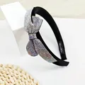 Close-up van luxe hoofdband met fonkelende strass-strik op een brede zwarte basis - AB Zirkoon