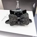 Nahaufnahme einer schwarzen Schleifen-Haarklammer mit Strass auf einer weißen Geschenkbox - Voll Strass Blase Kissen Haarklammer (Rotguss Schwarz)