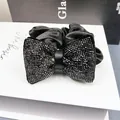 Vue macro d'une pince à cheveux en velours noir ornée d'un nœud en strass brillants - Chouchou Coussin à Bulles Strass (Noir Fusil)