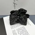 Dettaglio macro di un elegante fermaglio per capelli a fiocco nero con strass argentati - Elastico per capelli / Strass Nero Fucile