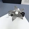 Dettaglio della pinza per capelli a fiore nero con strass luccicanti e perla centrale - Zircone AB