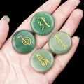 Green aventurine reiki stones with golden engraved symbols held in palm on black background - Green Aventurine