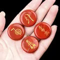 Red jasper Reiki stones set with golden healing symbols held in palm on black background - Red Jasper