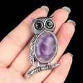 Antique silver owl necklace pendant with oval purple stone held in hand for scale - Amethyst