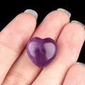 Polished 15mm natural purple amethyst heart stone held in hand against black background - Amethyst