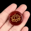 Polished red agate stone with gold lotus engraving held in hand for meditation - Red Agate