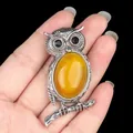 Antique style silver owl necklace with amber gemstone held by hand for scale - Agate