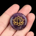 Hand holding a 25mm round purple amethyst energy stone with golden lotus engraving - Amethyst