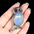 Antique silver owl necklace with iridescent blue opal stone held by hand on black backdrop - Opal (Synthetic)