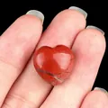 Polished natural red jasper stone in heart shape held between fingers for size - Red Jasper
