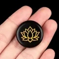 Black agate stone featuring a gold engraved lotus design held in palm for yoga decor - Obsidian