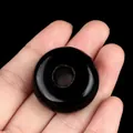 Polished black agate 30mm donut stone bead for jewelry making held by hand - Obsidian