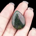 Teardrop moss agate crystal pendant with natural green inclusions held in hand - India Agate