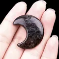 Croissant de lune en cristal noir poli avec reflets bleus et bronze dans la main - Pierre d'artifice