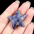 Blue natural stone starfish with smile engraving and marbled texture held in hand - Blue Sodalite