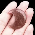 Pierre de lune en quartz fraise poli tenue à la main sur un fond noir profond - Aventurine violette