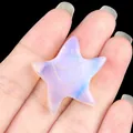 Carved white opal glass starfish charm with a smiling face held in hand - Synthetic Opal