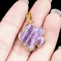 Hand holding a 20mm flower-shaped pendant with purple quartz gemstone and gold-plated edges - Amethyst