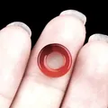 Translucent orange carnelian agate hollow round bead shown on fingertip for size - 10mm / Red Agate