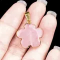 Pink rose quartz flower pendant with gold plated edge and bail held in hand - Rose Quartz