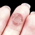 Pink natural strawberry quartz hollow circle bead charm held on a finger for size - 10mm / Strawberry Quartz