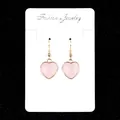 Pink heart-shaped drop earrings with golden frames on a white jewelry display card - Rose Quartz