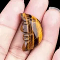 Carved natural tiger eye crescent moon face stone held in palm for size reference - Tiger's Eye