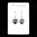 Golden heart earrings with natural grey speckled gemstone on a white jewelry display card - Larvikite