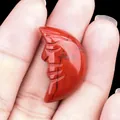 Handcrafted Red Jasper carved moon face stone pendant held in hand to show scale - Red Jasper