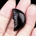 Polished black obsidian moon face carving held in hand for scale and detail - Obsidian