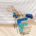Portachiavi lettera F in resina glitterata blu con ciondolo a farfalla e nappa blu - Blu F